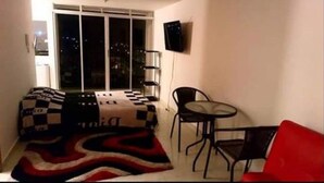 A small room with a bed, a chair, a table, and a TV on the wall. - Studio of a single environment (Armenia)