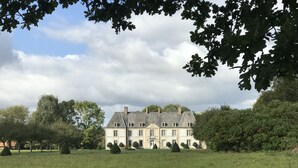 Un grand bâtiment historique à la façade symétrique, doté de nombreuses fenêtres et d’une entrée centrale.