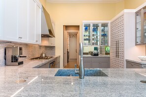 Cozinha moderna com bancadas de granito, máquina de café expresso embutida e backsplash com detalhes em azul.
