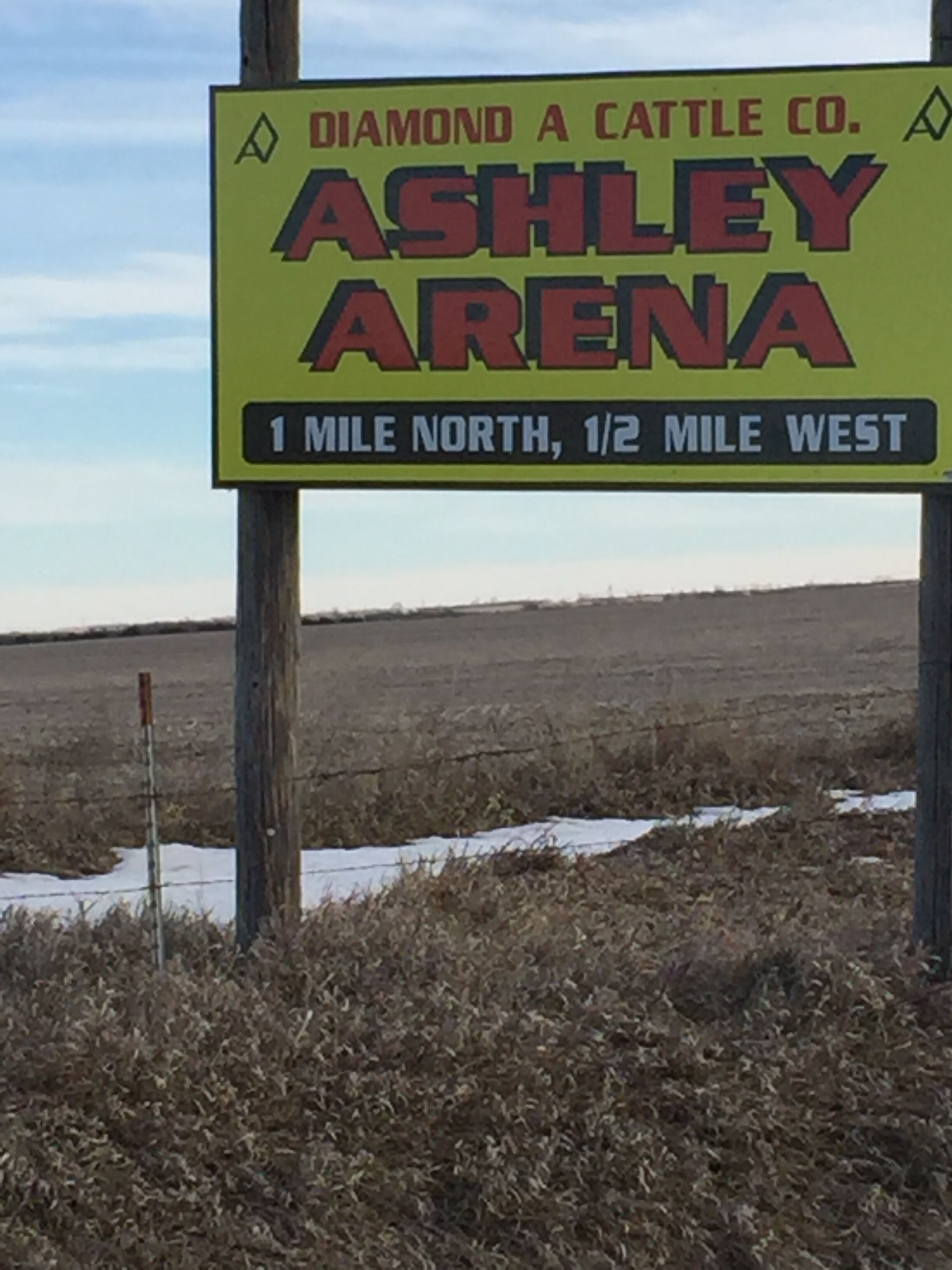A sign for Ashley Arena, a venue for Diamond A Cattle Co., with directional information.