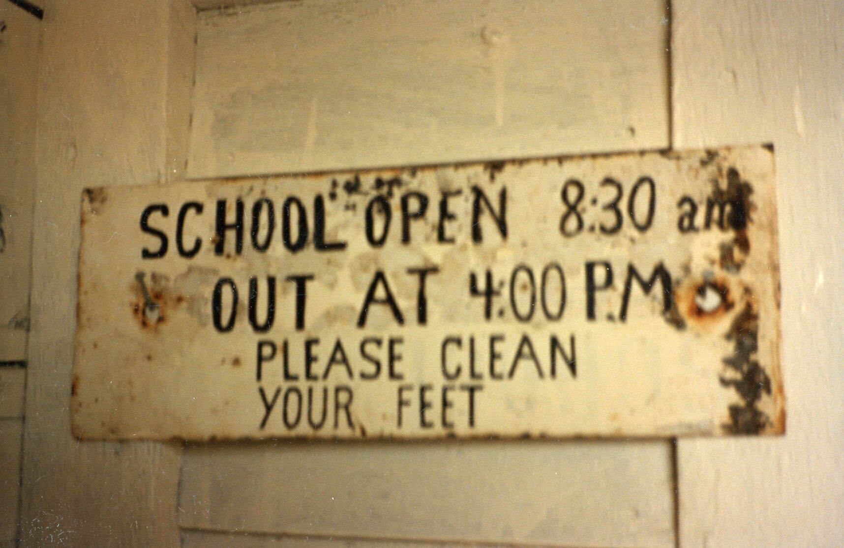 A sign indicating school hours and a request to clean feet.