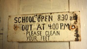 A sign indicating school hours and a request to clean feet.