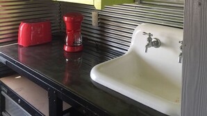 Une salle de bain avec une porte verte, un lavabo blanc et un objet rouge posé sur le comptoir.