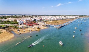 Vista aérea de un pueblo costero con un puerto deportivo, barcos y edificios a lo largo de la costa.