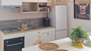 Una cocina moderna con armarios blancos, una isla central y dos lámparas de mimbre colgantes.