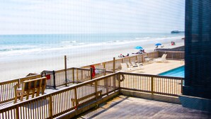 A beach view from a balcony with a pool, wooden deck, and beach chairs. - Sea Oaks Oceanfront 2-Bed / 2-Bath (Garden City)