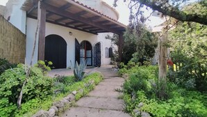 A pathway leading to a building with a covered porch and multiple doors.