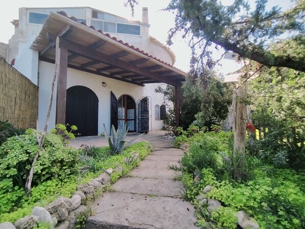 Un camino que lleva a un edificio con porche cubierto y varias puertas.