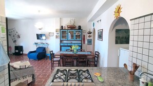 A kitchen with a gas stove, a dining table with chairs, and a blue sofa in the living area.