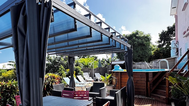 An outdoor patio area with a pool, wooden deck, and outdoor seating. - VILLA C'MARGOT - 110 M2 (MARIGOT)
