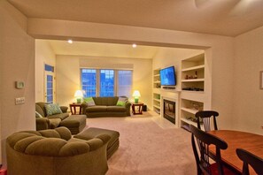 Una sala de estar con sofá, televisor, chimenea y mesa de comedor.