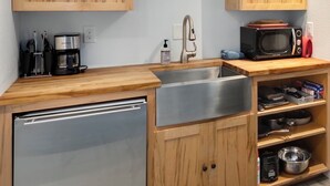 A compact kitchen with wooden cabinets, a stainless steel sink, a microwave, and a dishwasher.