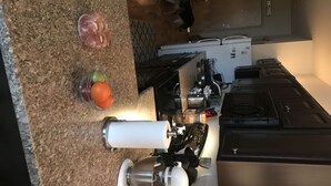 Una cocina con encimera de granito, un exprimidor de jugos, una licuadora y un refrigerador.
