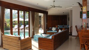 Amplia sala de estar con vista a la piscina, muebles de madera y zona de comedor.