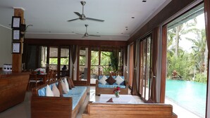 Amplia sala de estar con un sofá grande, muebles de madera y vista a una piscina.