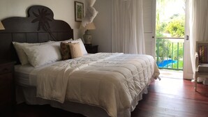 A bedroom with a large bed, a canopy, a view of a balcony, and a door leading outside. - Cotton Bay Townhouse (Gros Islet)