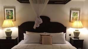 A neatly made bed with white linens and a dark headboard, flanked by two bedside tables with lamps. - Cotton Bay Townhouse (Gros Islet)