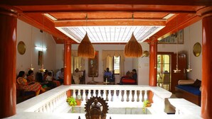 Una habitación con una estatua central, pilares de madera y un balcón con barandilla.
