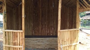 Estructura de bambú con una entrada cubierta y un colorido felpudo en la base.