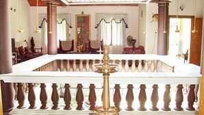 Una habitación con un pilar central, baranda blanca y vista hacia un comedor con sillas y mesas.
