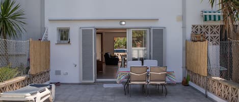 Un edificio de dos pisos con piscina, asientos exteriores y un patio cubierto.
