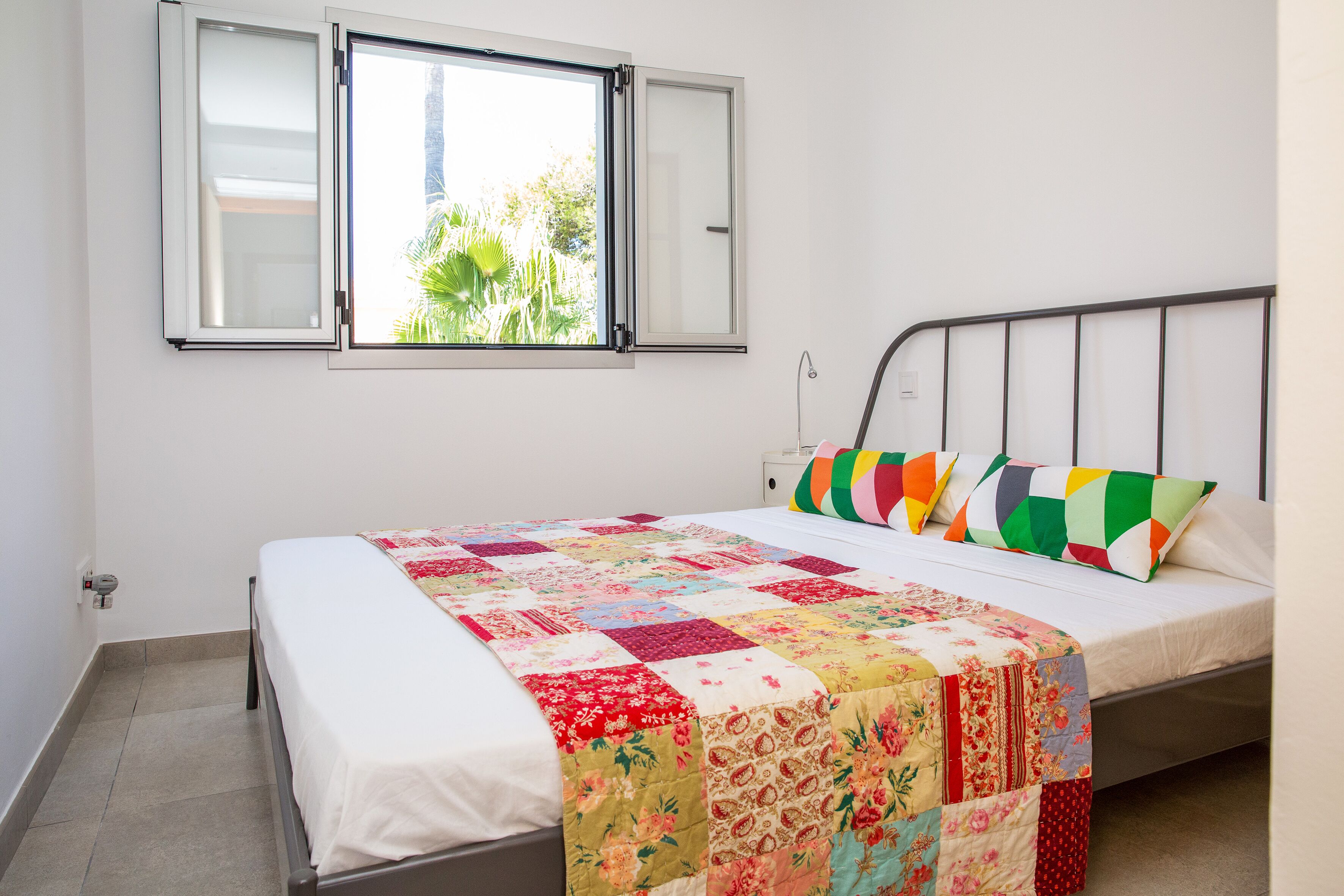 A bedroom with a bed, a window, and a view of greenery outside.