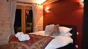 A bedroom with a bed, a wooden door, and a red wall. - Boutique Alpine Chalet with Panoramic Views next to Ski Lift (Thollon-Les-Mémises)