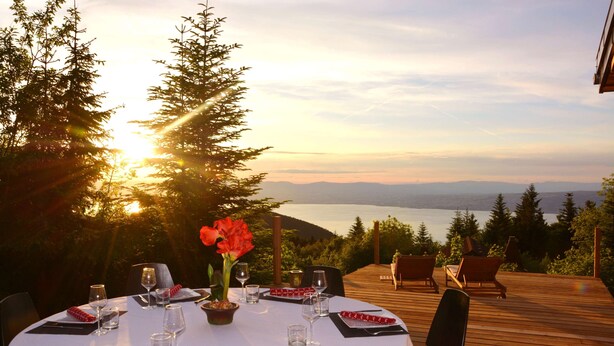 A round dining table set outdoors with a view of the ocean and mountains. - Boutique Alpine Chalet with Panoramic Views next to Ski Lift (Thollon-Les-Mémises)