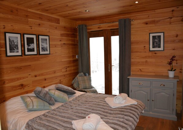 A wooden-paneled room with a bed, a dresser, and three framed pictures on the wall. - Boutique Alpine Chalet with Panoramic Views next to Ski Lift (Thollon-Les-Mémises)