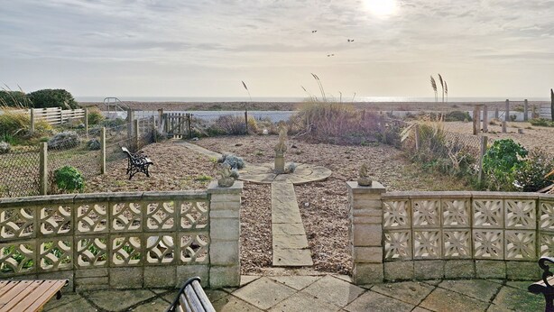 Une vue sur la côte, avec une terrasse en bois, un sentier en pierre et un espace clos agrémenté de bancs.