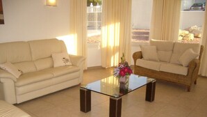A living room with a beige sofa, a wicker sofa, and a glass coffee table. - Casa del Erizo: Moraira. (Moraira)