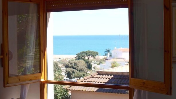 Une pièce dotée d’une grande fenêtre donnant sur la mer et une ville côtière.
