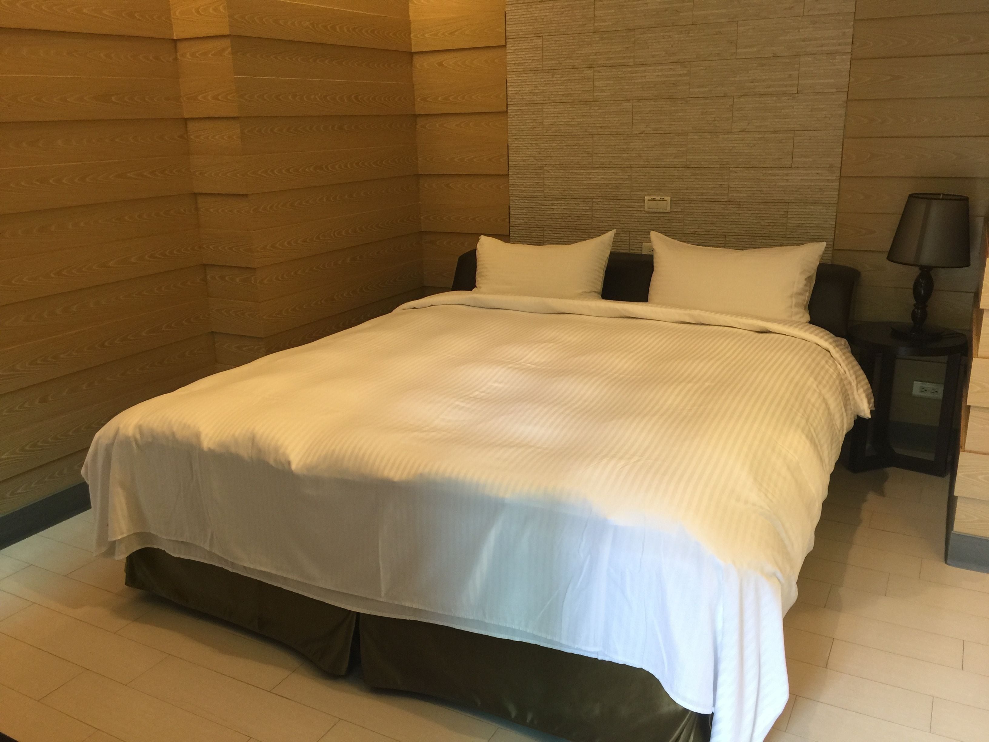 Una cama bien hecha con ropa de cama blanca en una habitación de hotel.