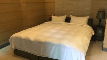 Una cama bien hecha con ropa de cama blanca en una habitación de hotel.