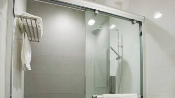 Une salle de bain moderne avec une douche à parois de verre, des toilettes blanches et un porte-serviettes sur lequel est posée une serviette.