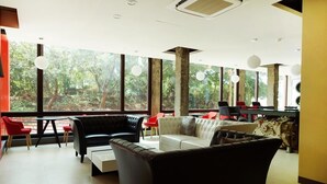 Un intérieur moderne avec un coin salon, de grandes fenêtres et une vue sur la verdure.