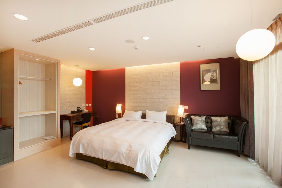 Ein Hotelzimmer mit Bett, Schreibtisch, Sofa und Kleiderschrank.