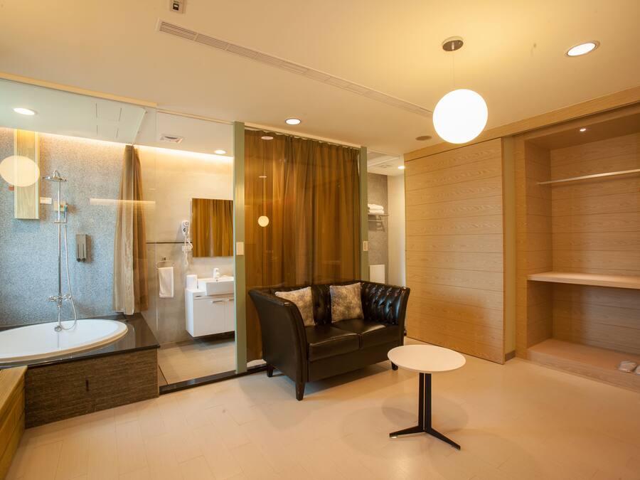 A modern bathroom with a bathtub, a black leather sofa, and a small round table.