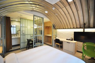 Una habitación de hotel con cama, escritorio, silla y televisor.