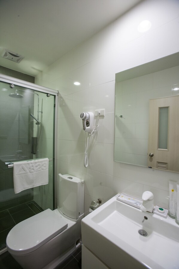 A modern bathroom with a glass-enclosed shower, a white toilet, a sink with a mirror, and a hairdryer mounted on the wall. - 823 Tourist Hotel (Jinhu)