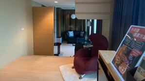 Une chambre d’hôtel avec un lit, un fauteuil rouge, une petite table et une affiche au mur.