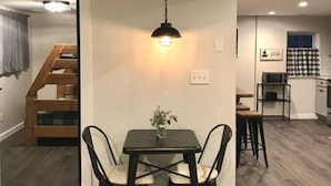 Un espace repas comprenant une table et des chaises, un luminaire suspendu et un escalier menant à une autre pièce.