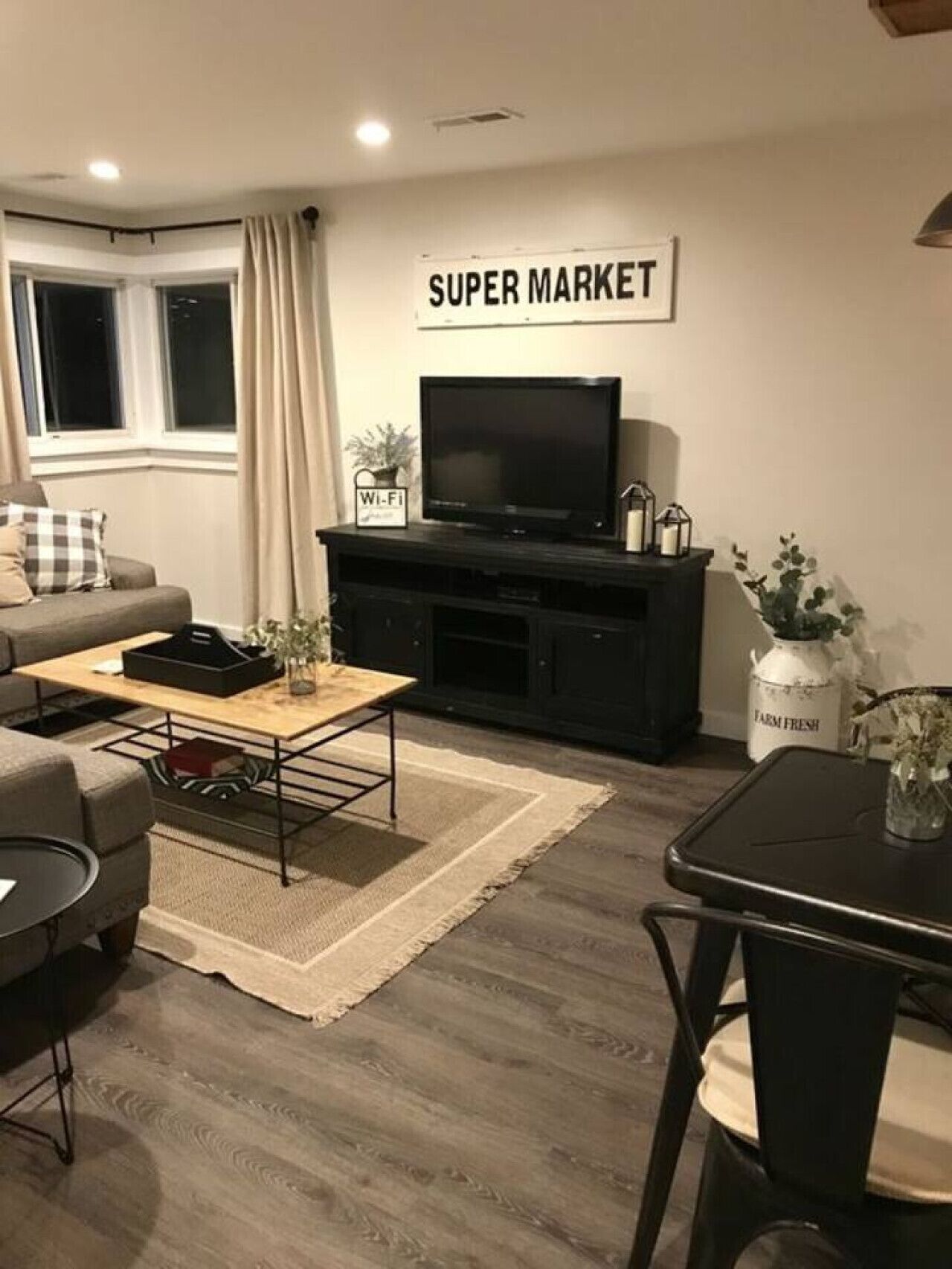 A living room with a sofa, coffee table, TV, and a sign that reads "SUPER MARKET".
