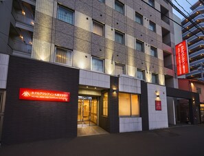Um hotel com fachada moderna, várias varandas e sinalização iluminada.