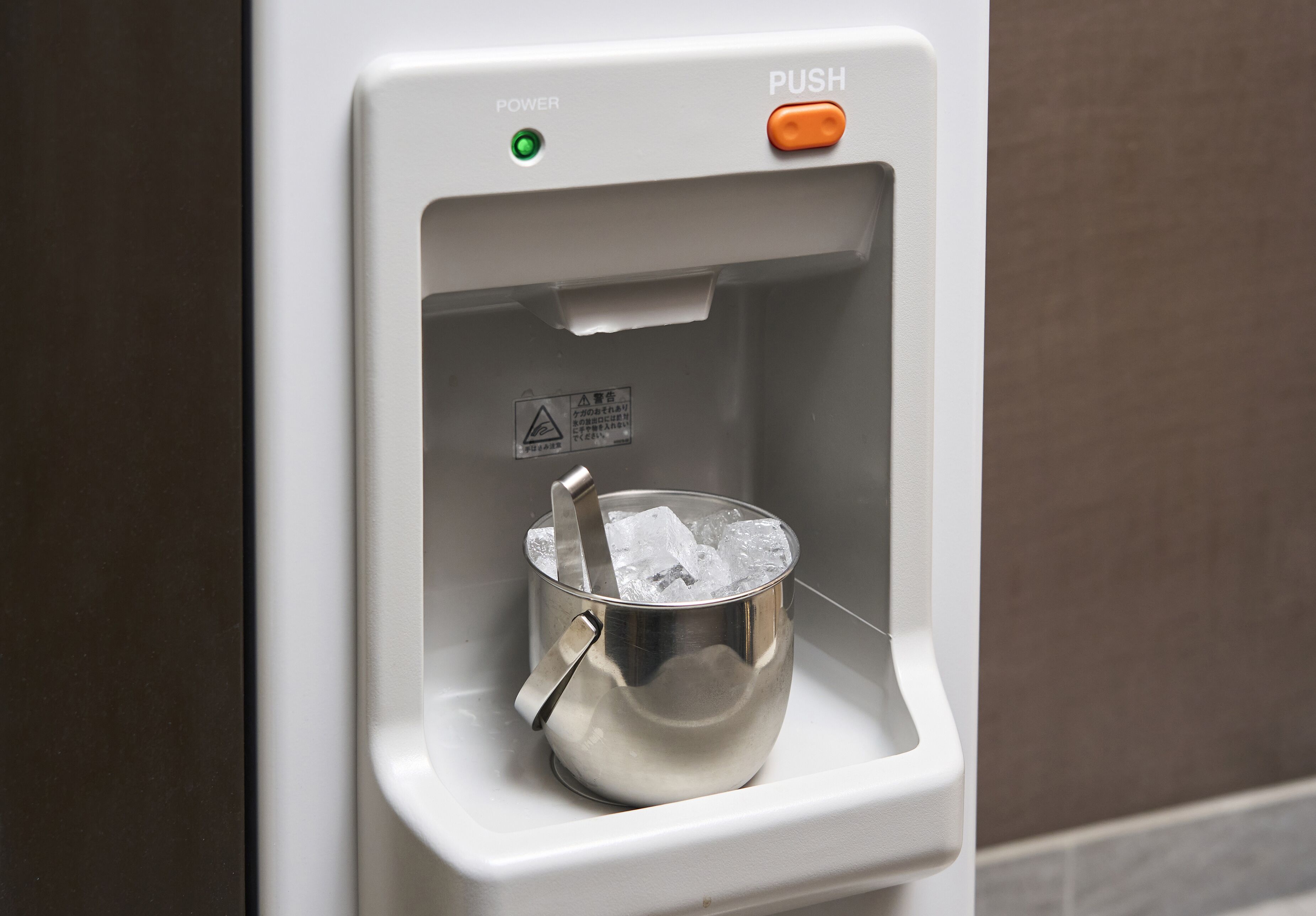 A water dispenser with a metal bucket containing ice cubes.
