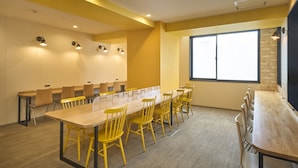 A conference room with a long table and yellow chairs, equipped with built-in lighting, a large window, and a brick accent wall. - HOTEL AXIA INN SAPPORO SUSUKINO  (Sapporo)