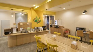 A modern dining area with a long wooden table, yellow chairs, and a central island with food and drink items. - HOTEL AXIA INN SAPPORO SUSUKINO  (Sapporo)