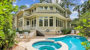 A two-story house with a large backyard featuring a swimming pool and outdoor furniture. - Beautiful & Spacious 5br Home w/ Private Pool (Hilton Head Island)