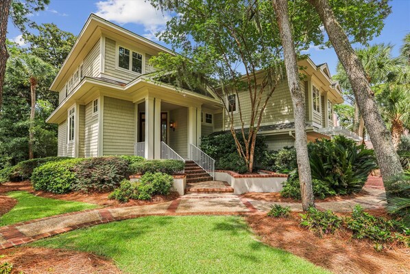 A two-story house with a front porch, a brick pathway leading to the entrance, and a well-maintained lawn.