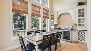 A dining area with a table set for four, surrounded by white cabinetry and a large window with bamboo blinds. - Beautiful & Spacious 5br Home w/ Private Pool (Hilton Head Island)